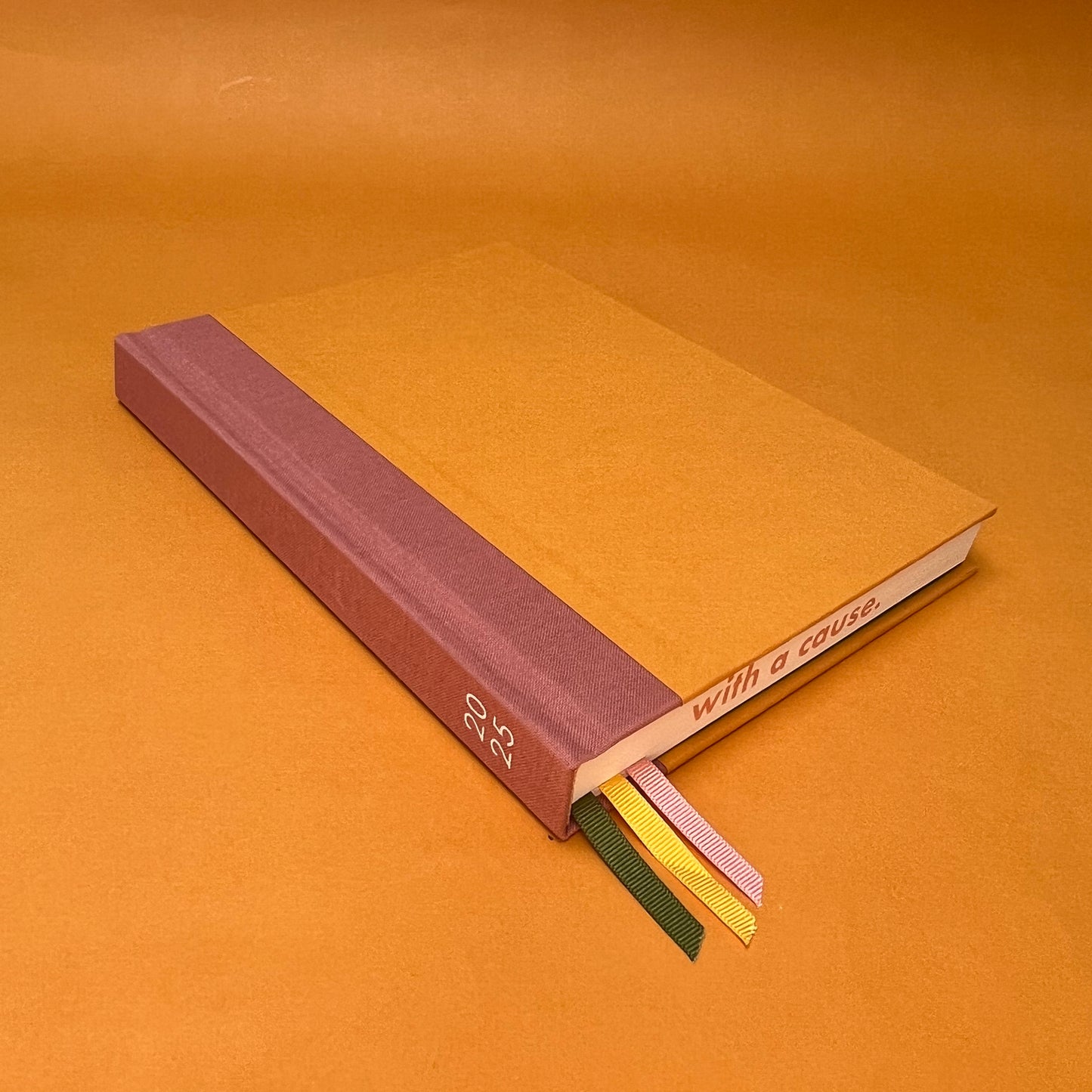 Rebel Stationery's Seasonal Gold notebook, a yellow A5 with pink linen spine, on a yellow background