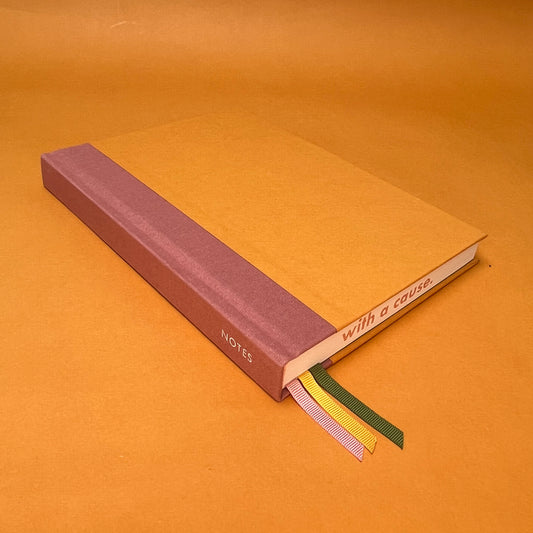 Rebel Stationery's Seasonal Gold notebook, a yellow A5 with pink linen spine, on a yellow background