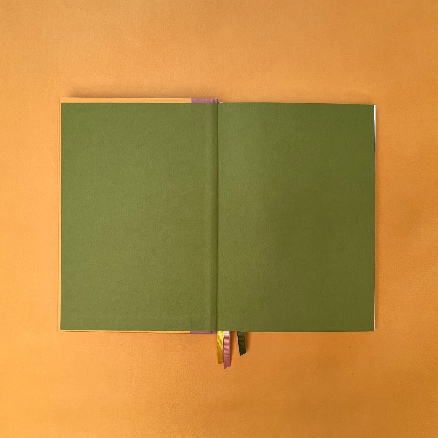 Green endpapers of Rebel Stationery's Gold Seasonal notebook (yellow cover with pink linen spine) on a yellow background