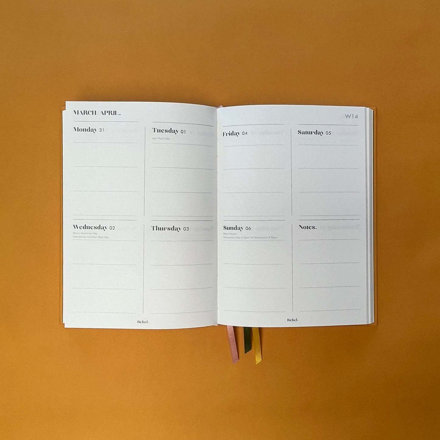 WTV spread of Rebel Stationery's Gold Seasonal notebook (yellow cover with pink linen spine) on a yellow background