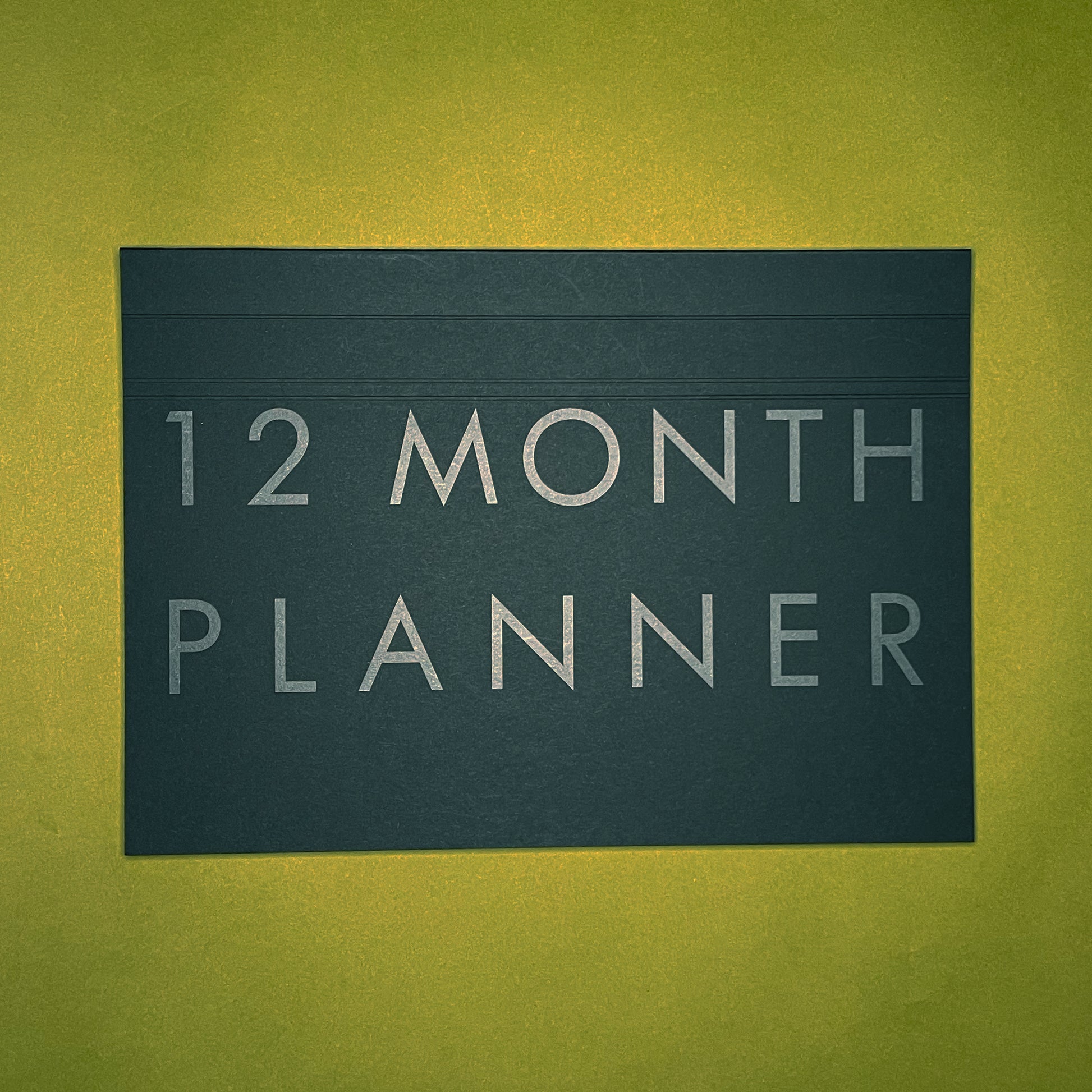 Front cover of Rebel Stationery's A4 Monthly Desk Planner in Ink on green background