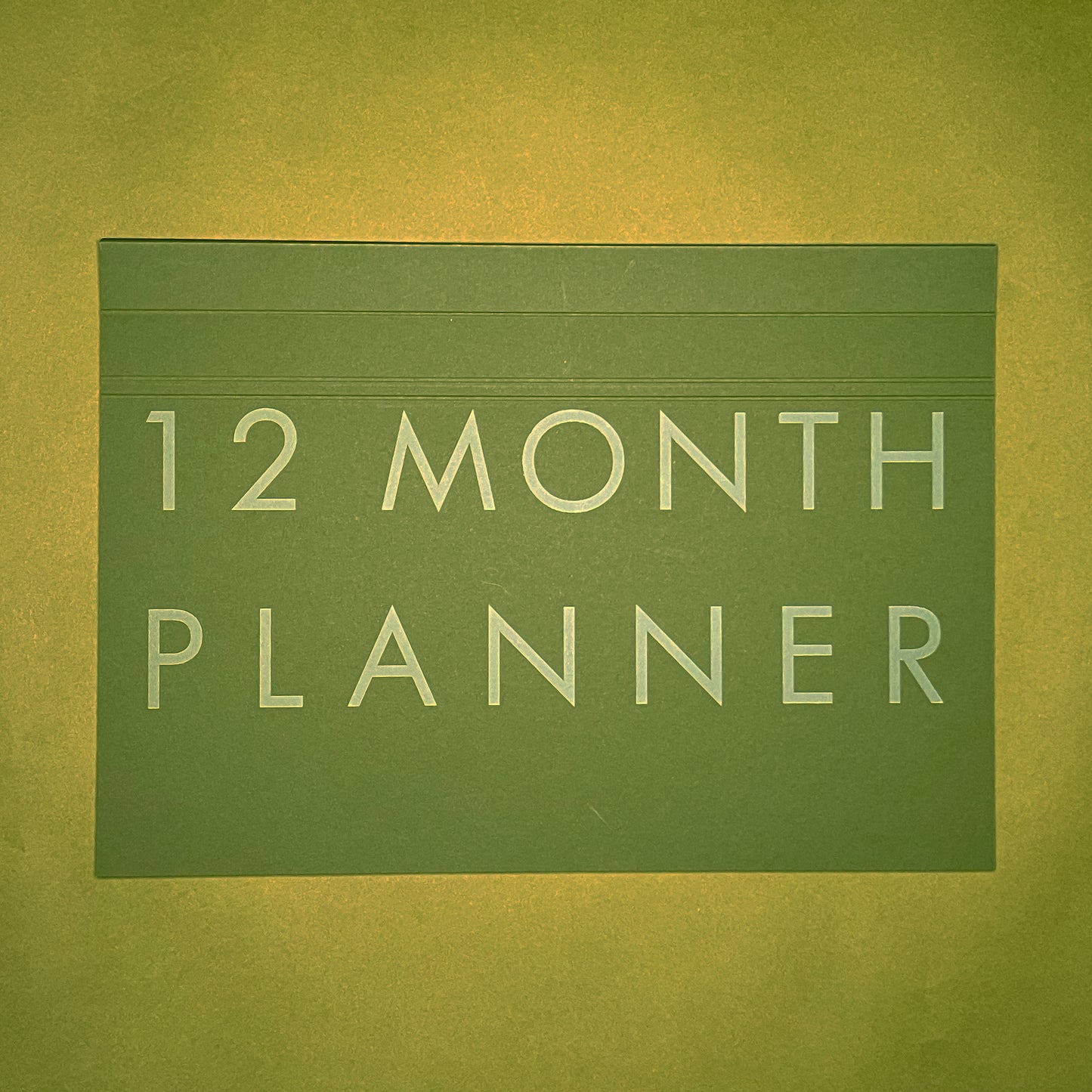 Front cover of Rebel Stationery's A4 Monthly Desk Planner in Moss on green background