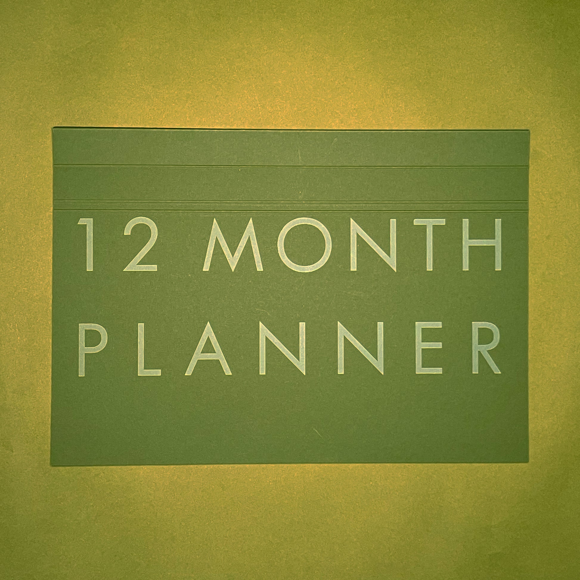 Front cover of Rebel Stationery's A4 Monthly Desk Planner in Moss on green background