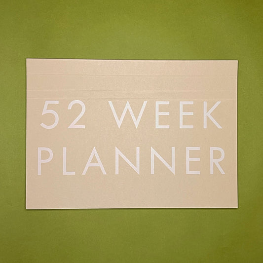 Front cover of Rebel Stationery's Weekly Desk Planner in Stone on a green background