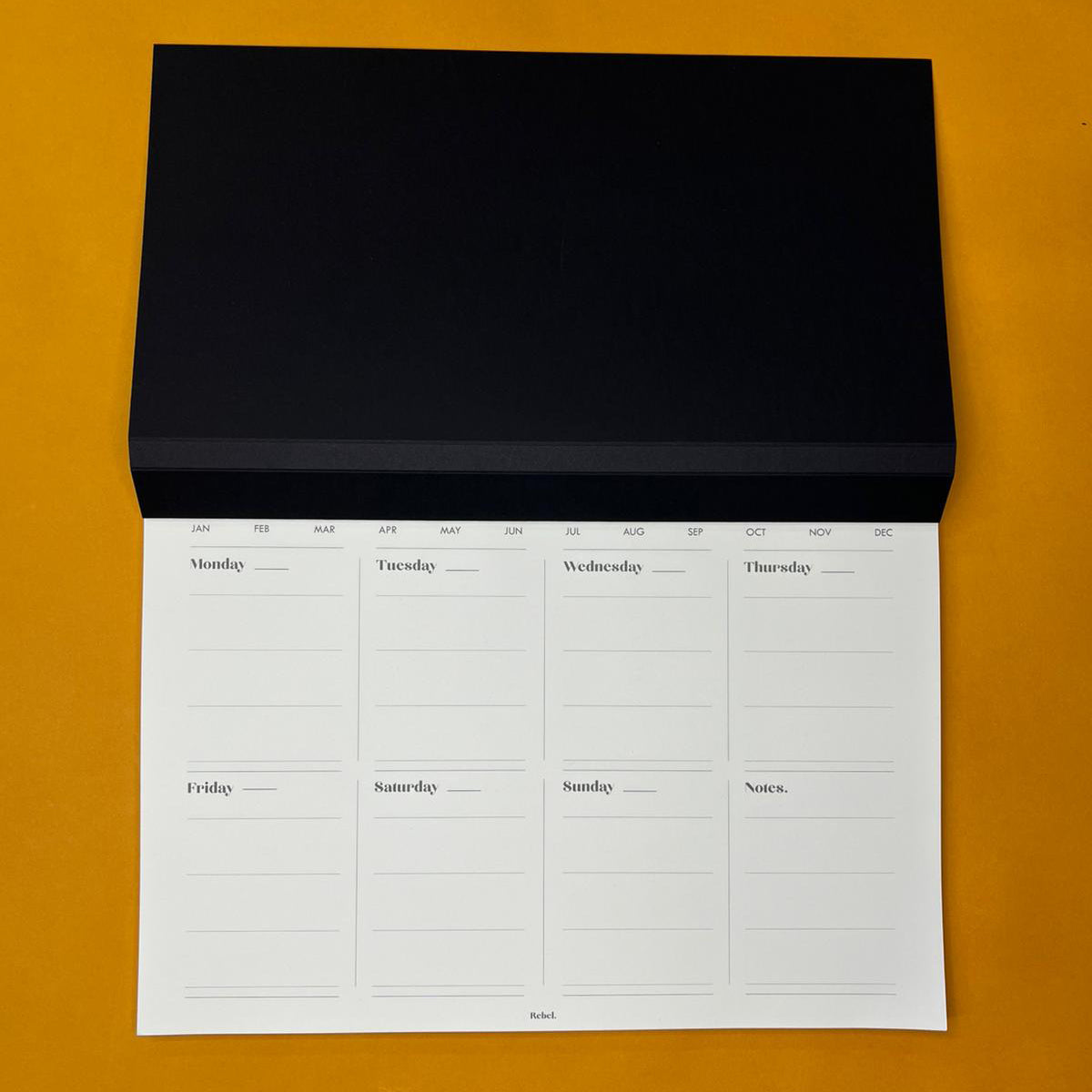 Black desk planner with weekly text on yellow background