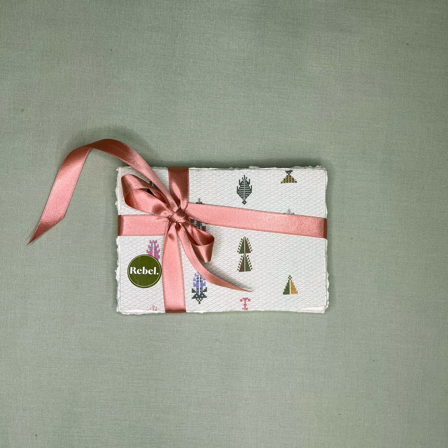 Pack of patterned notelets with a pink ribbon on a green background
