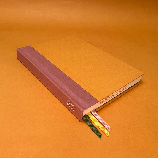 Rebel Stationery's Seasonal Gold notebook, a yellow A5 with pink linen spine, on a yellow background