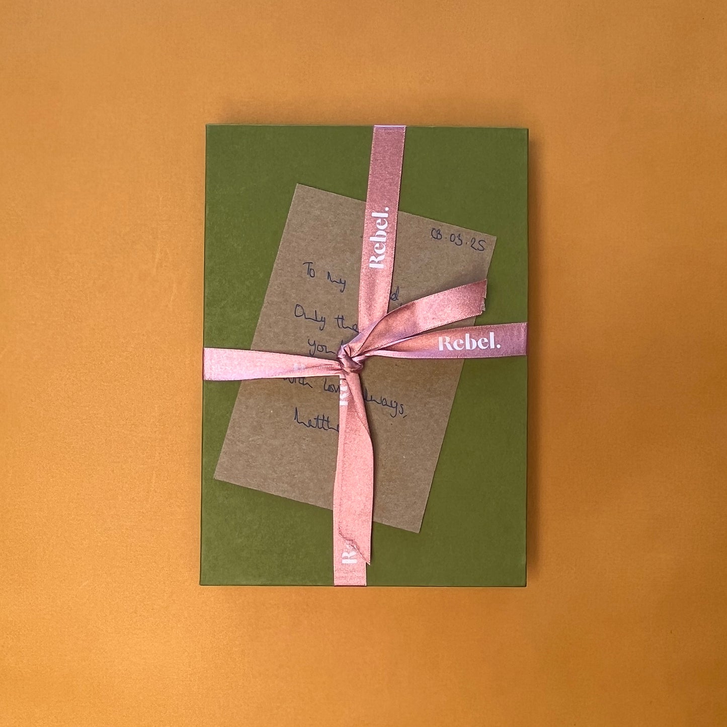 Rebel Stationery's Gift wrap option of green slipcase, branded peach ribbon, and handwritten message on Kraft card, on a yellow background