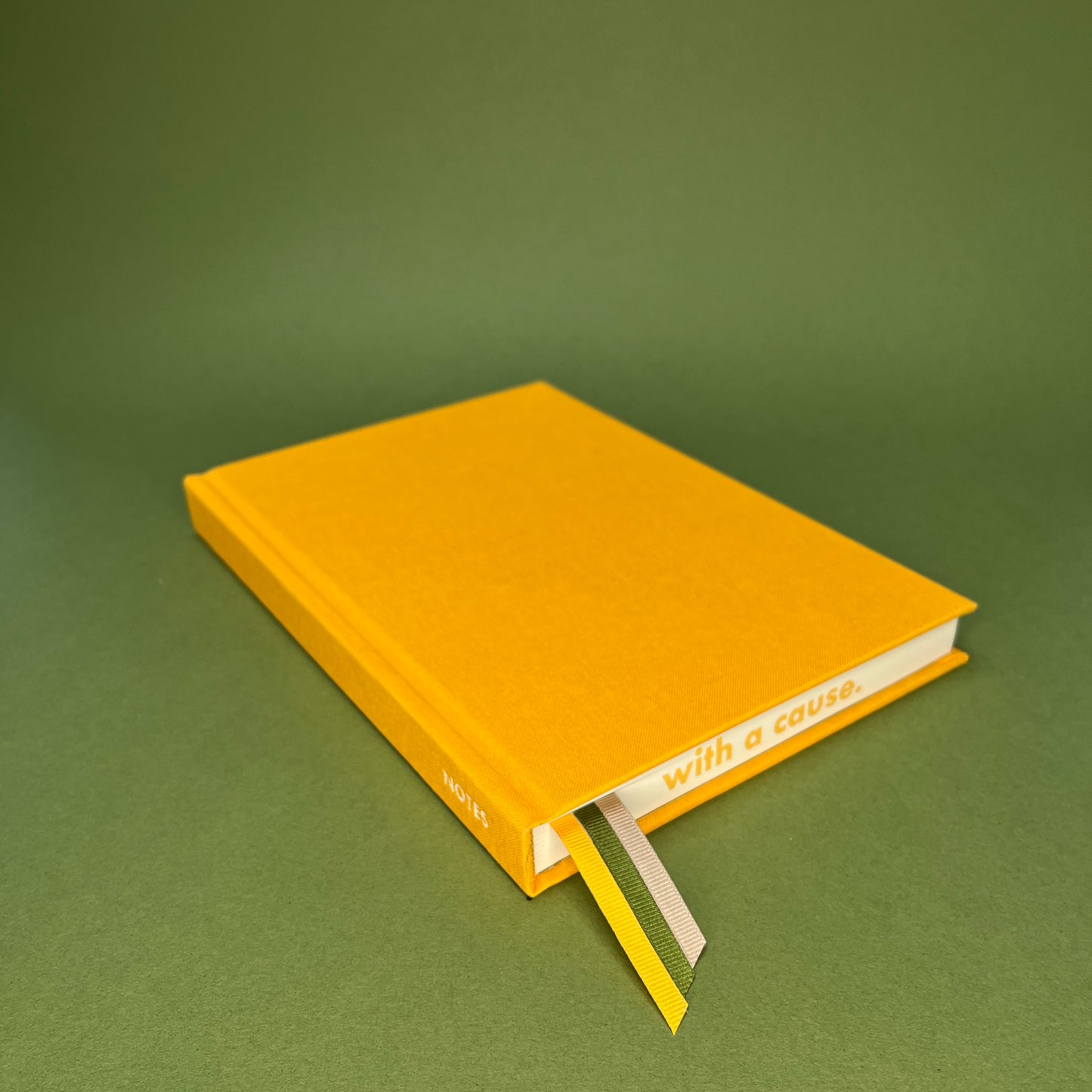 Rebel Stationery's Signature A5 notebook in yellow bookcloth, on a green backround