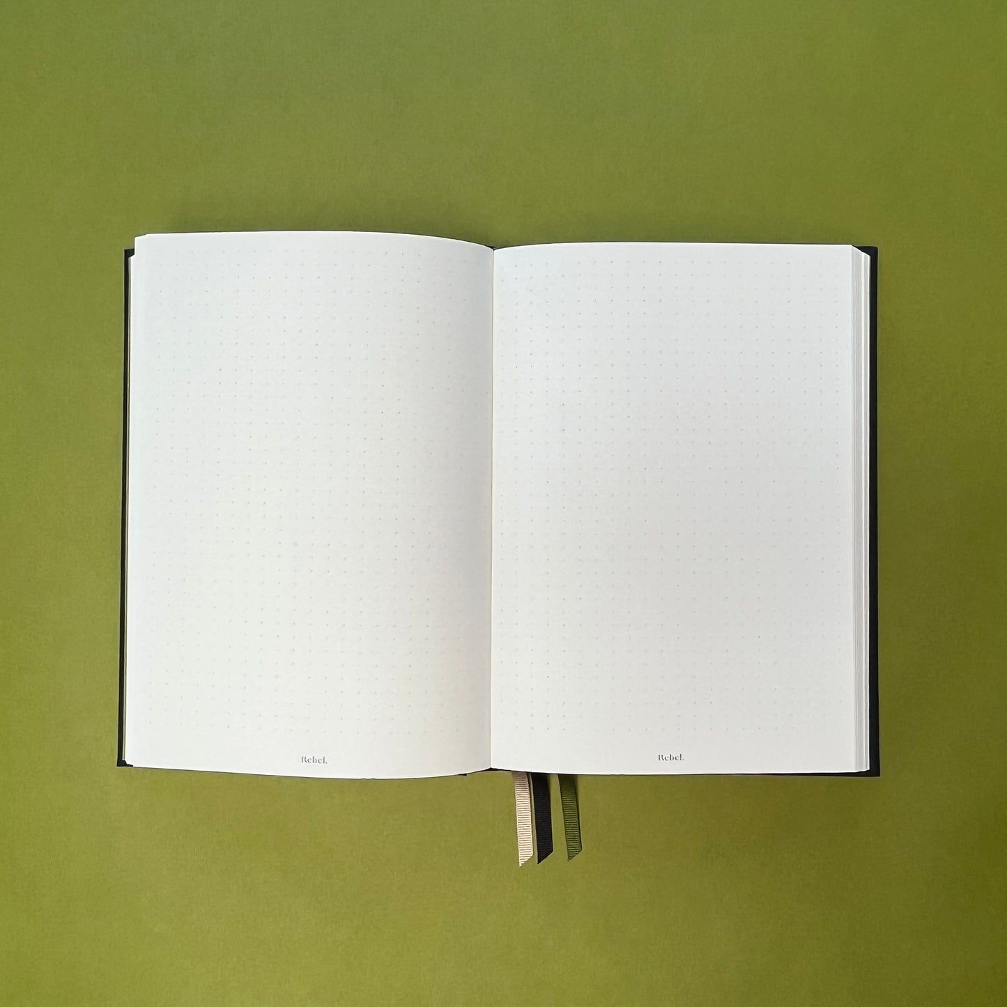Dotted spread of Rebel Stationery's Signature notebook in Ink on green background