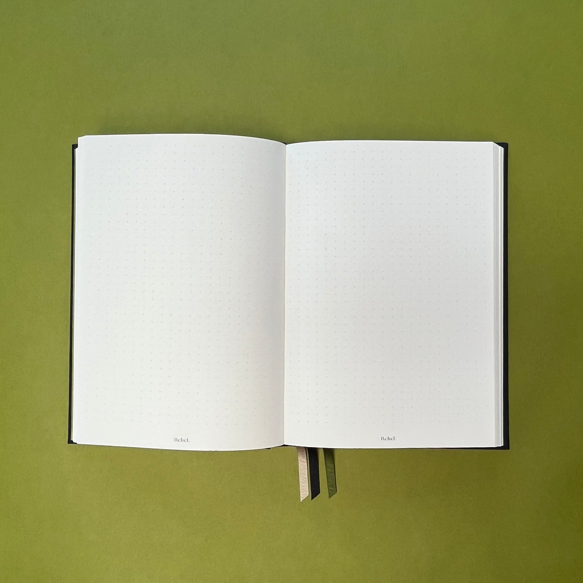 Dotted spread of Rebel Stationery's Signature notebook in Ink on green background