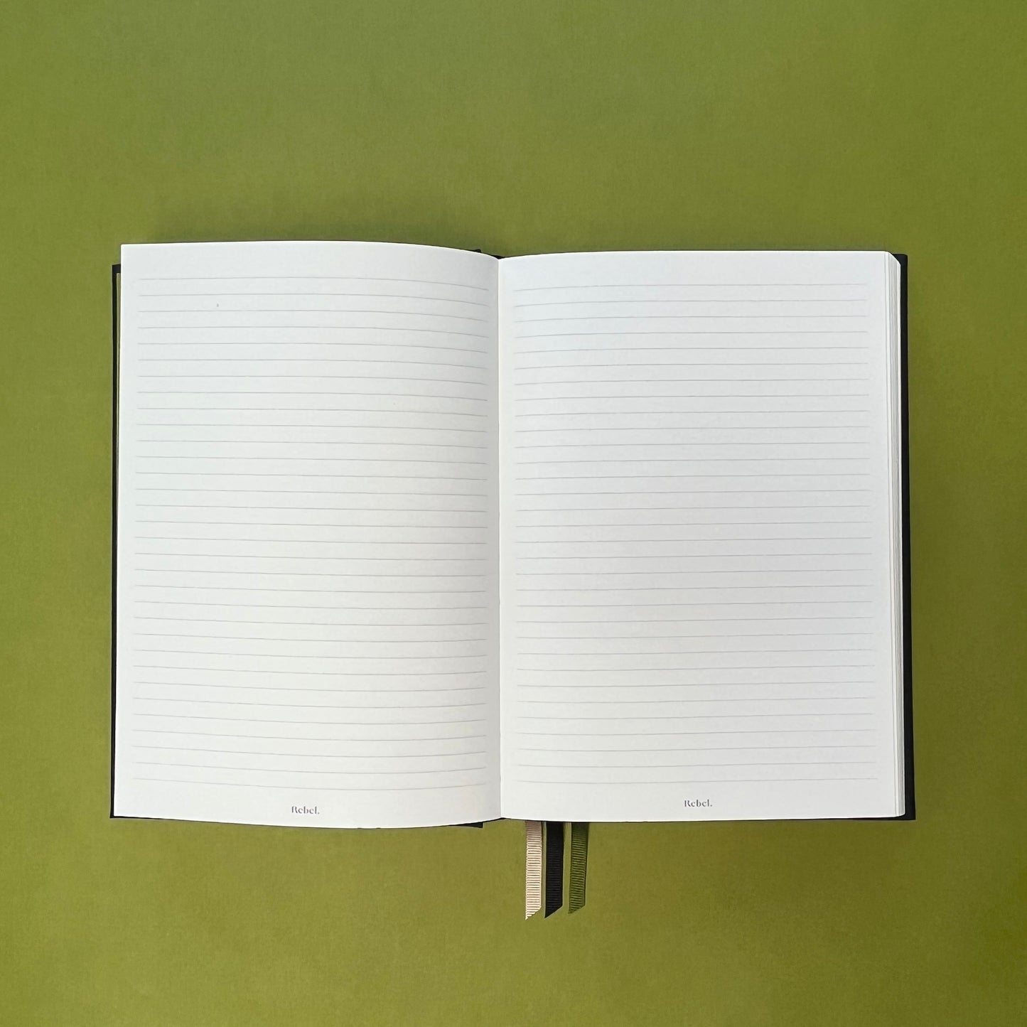 Lined spread of Rebel Stationery's Signature notebook in Ink on green background
