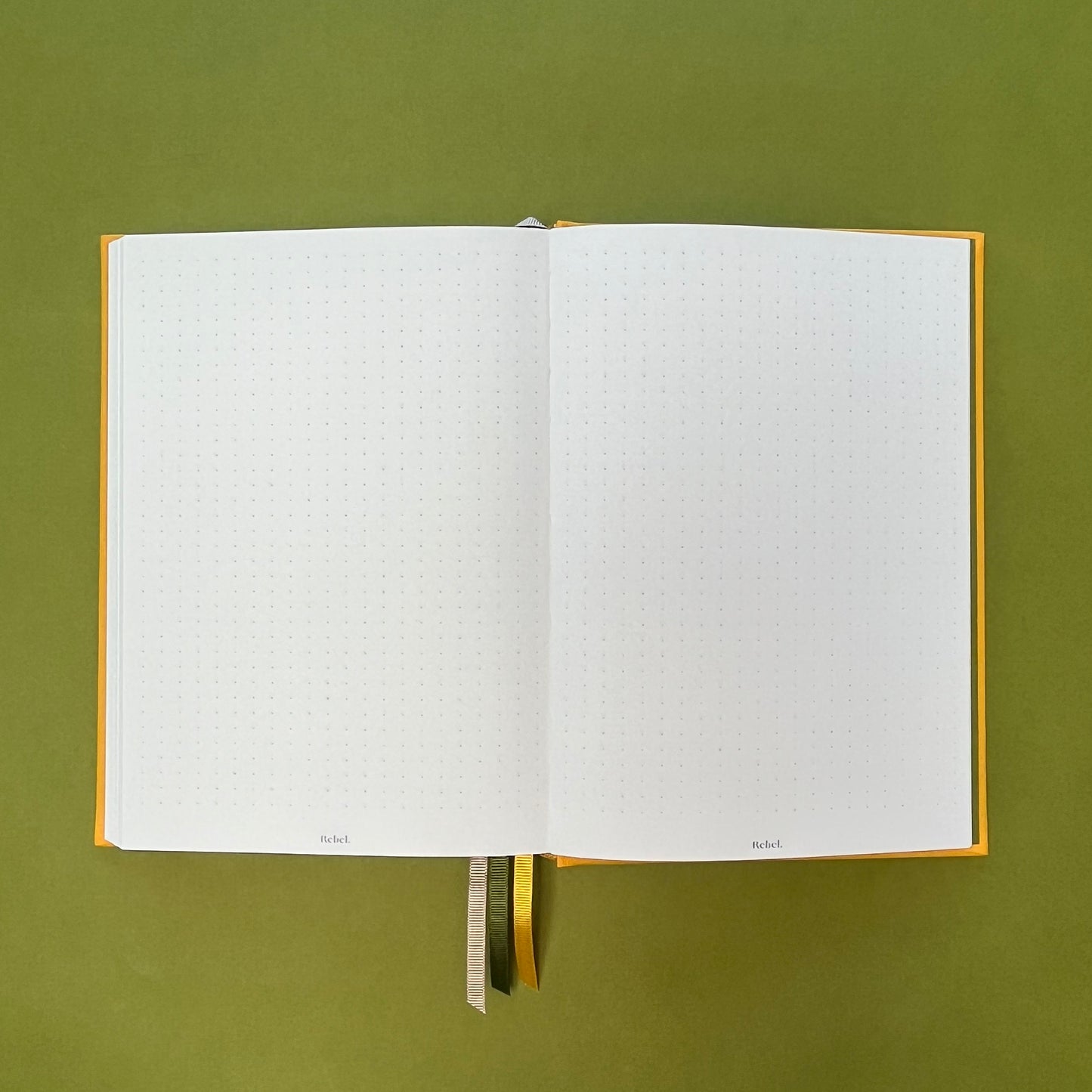 Dotted spread of Rebel Stationery's Signature A5 notebook in yellow bookcloth, on a green background