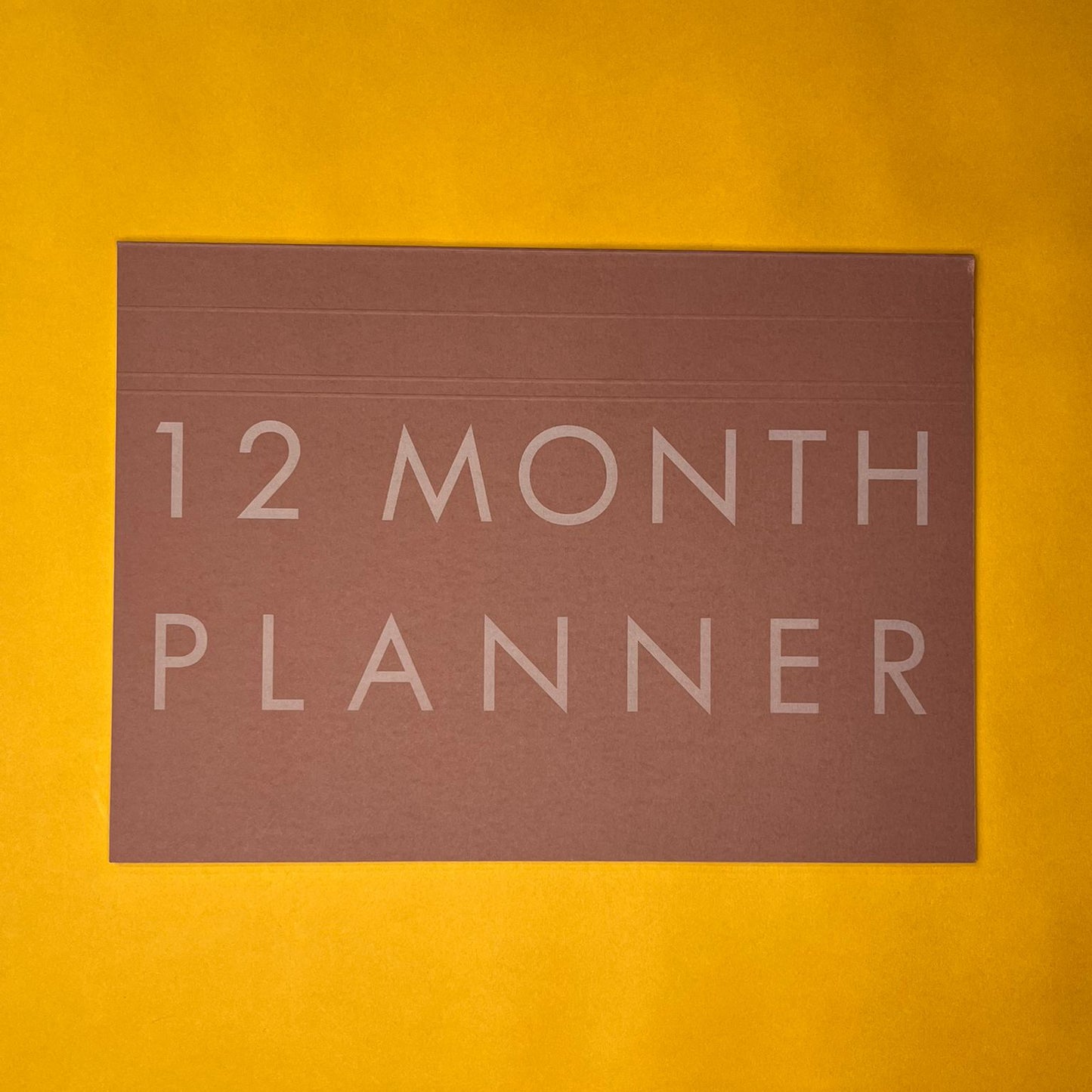 Pink desk planner with printed text on yellow background