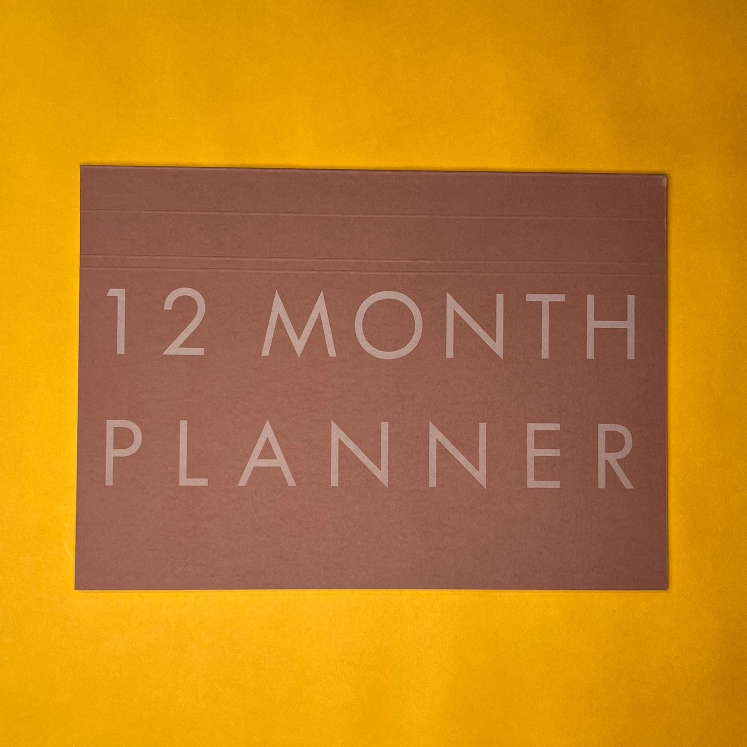 Pink desk planner with printed text on yellow background