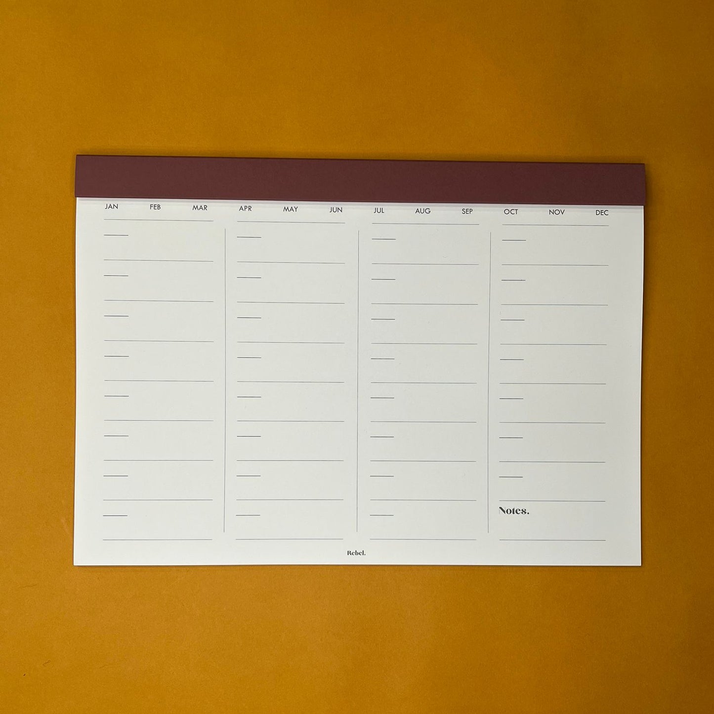 Pink desk planner with monthly layout on yellow background