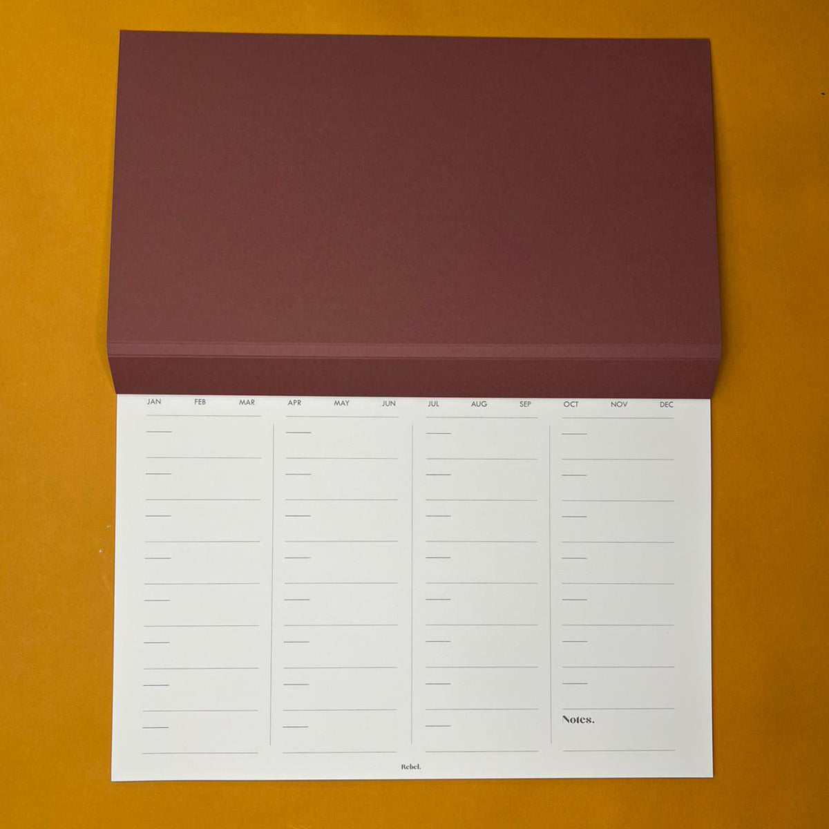 Pink desk planner with monthly layout on yellow background