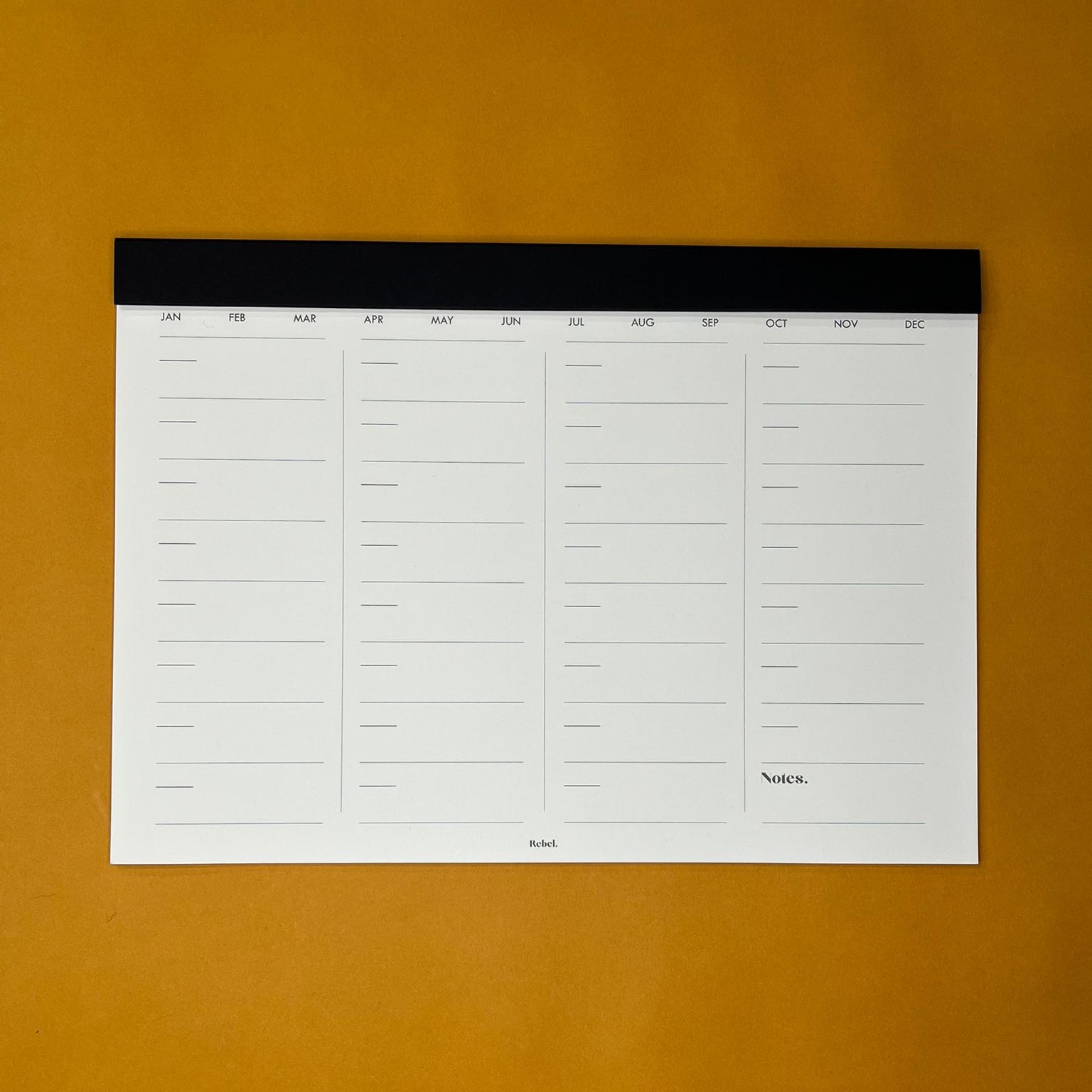 Black desk planner with monthly layout on yellow background