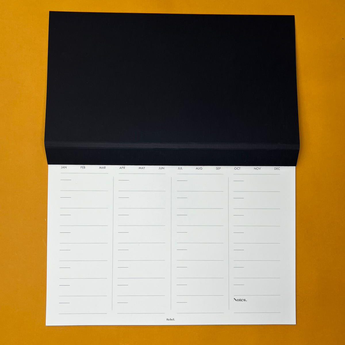 Black desk planner with monthly layout on yellow background