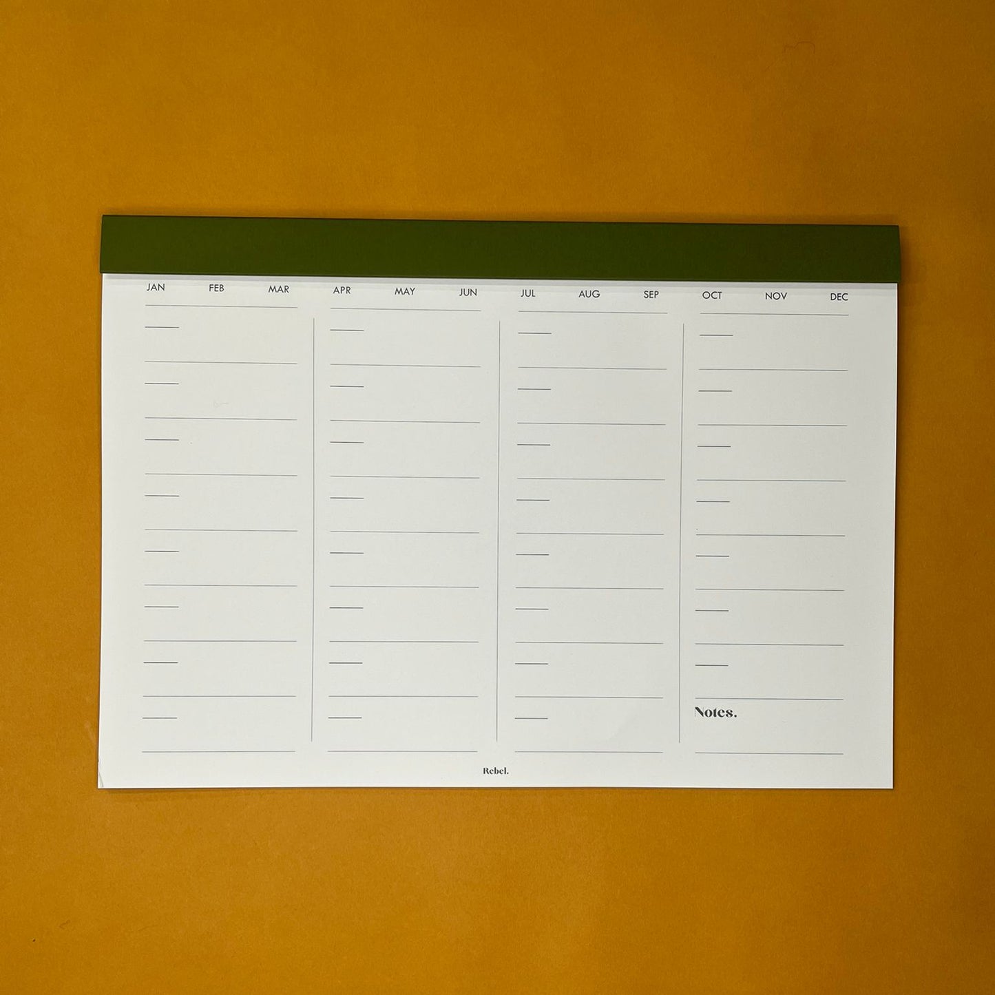 Green desk planner with monthly layout on yellow background