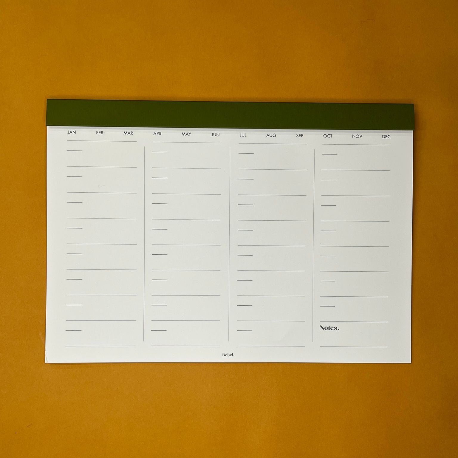 Green desk planner with monthly layout on yellow background