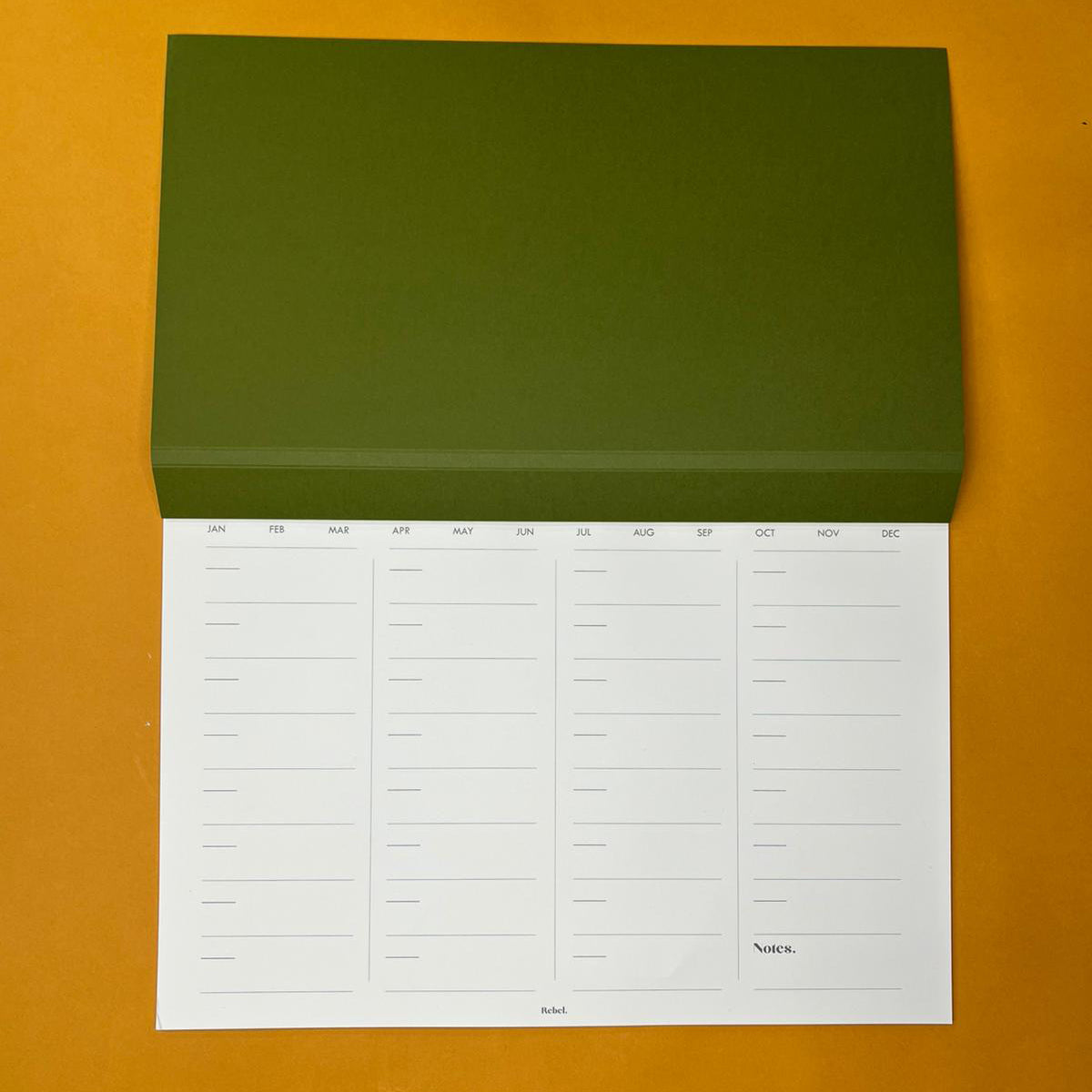 Green desk planner with monthly layout on yellow background