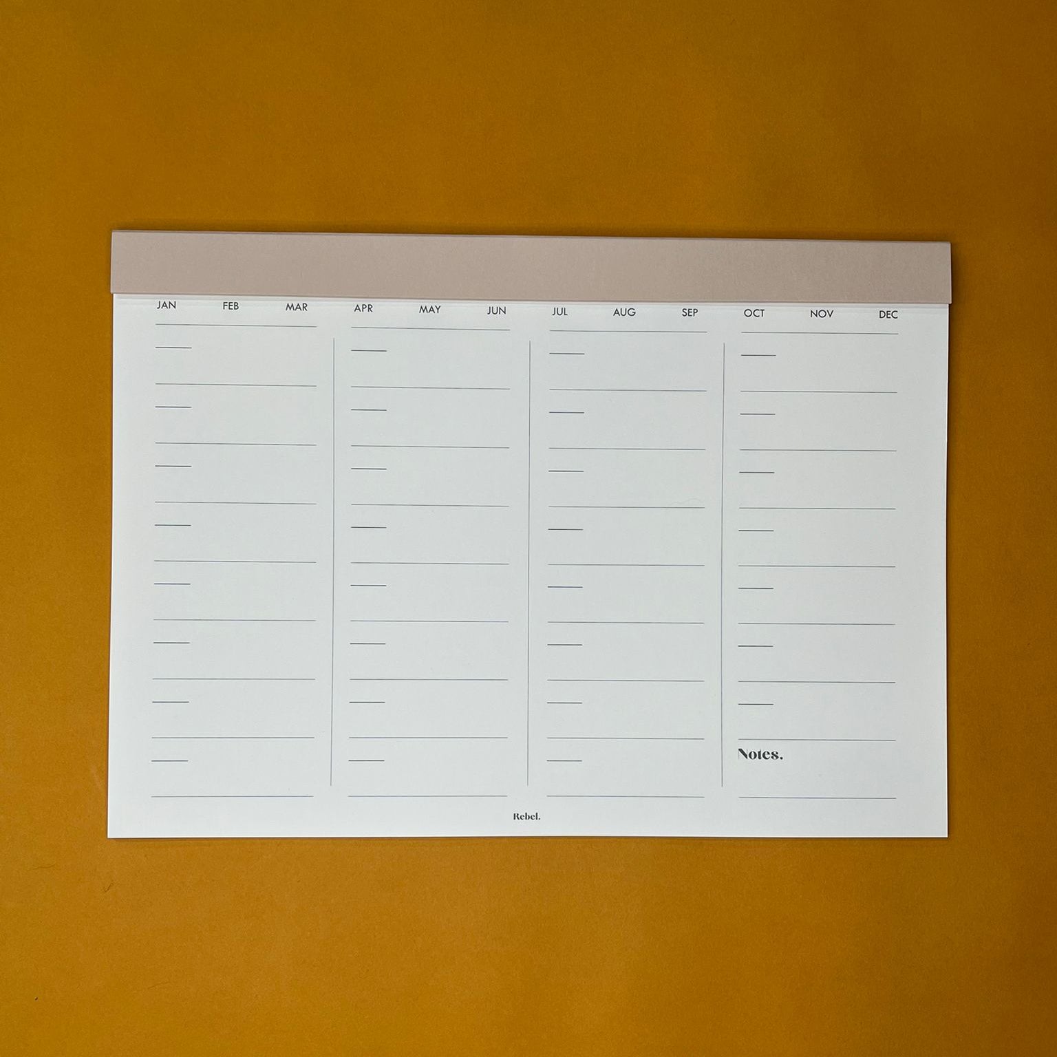 Beige desk planner with monthly layout on yellow background