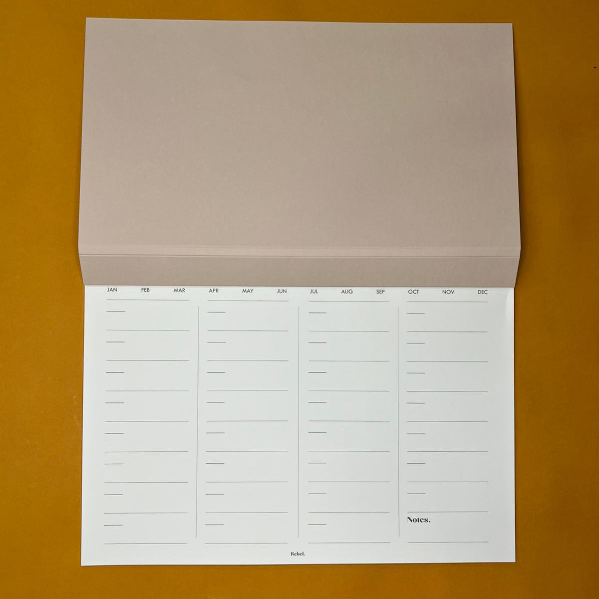 Beige desk planner with monthly layout on yellow background