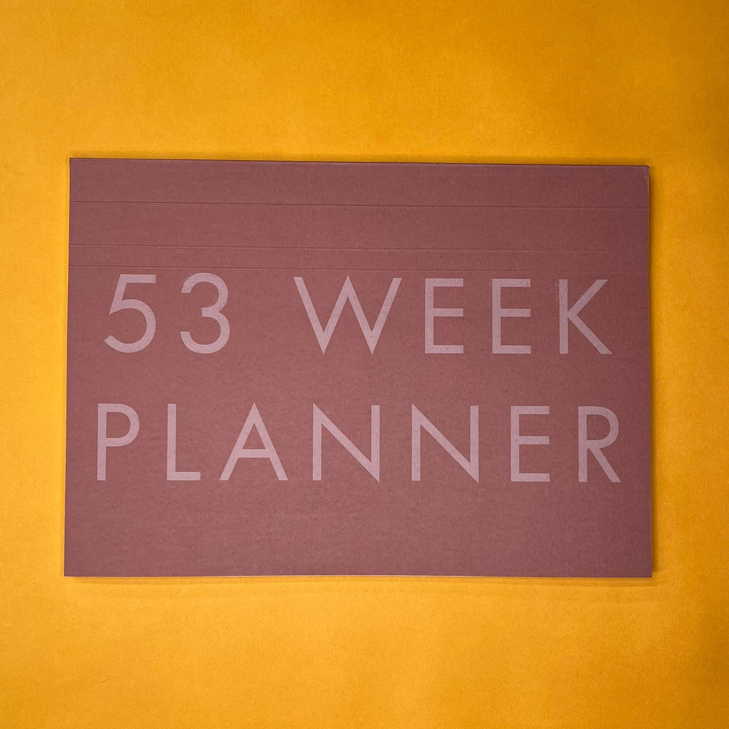 Pink desk planner with printed text on yellow background