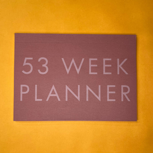 Pink desk planner with printed text on yellow background