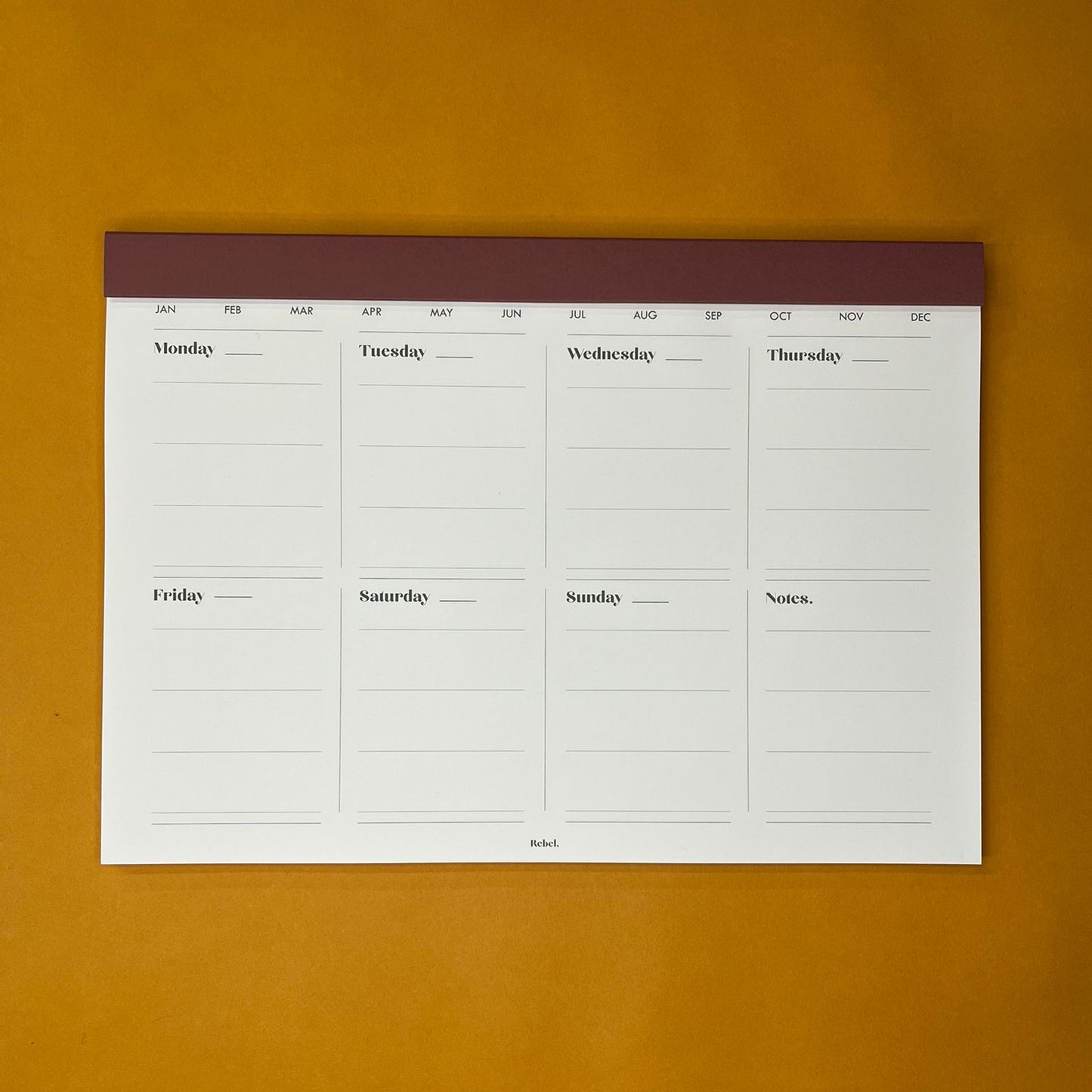Pink desk planner with weekly layout on yellow background