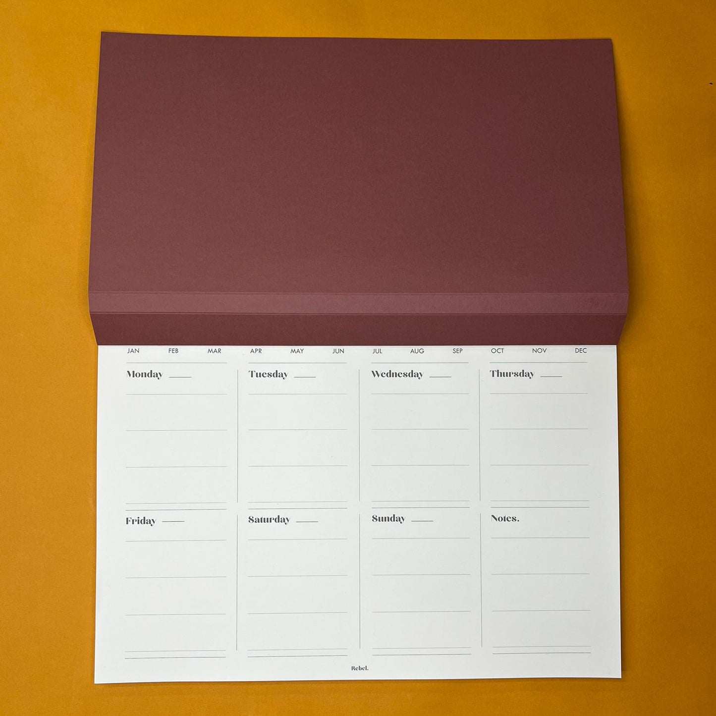 Pink desk planner with weekly layout on yellow background