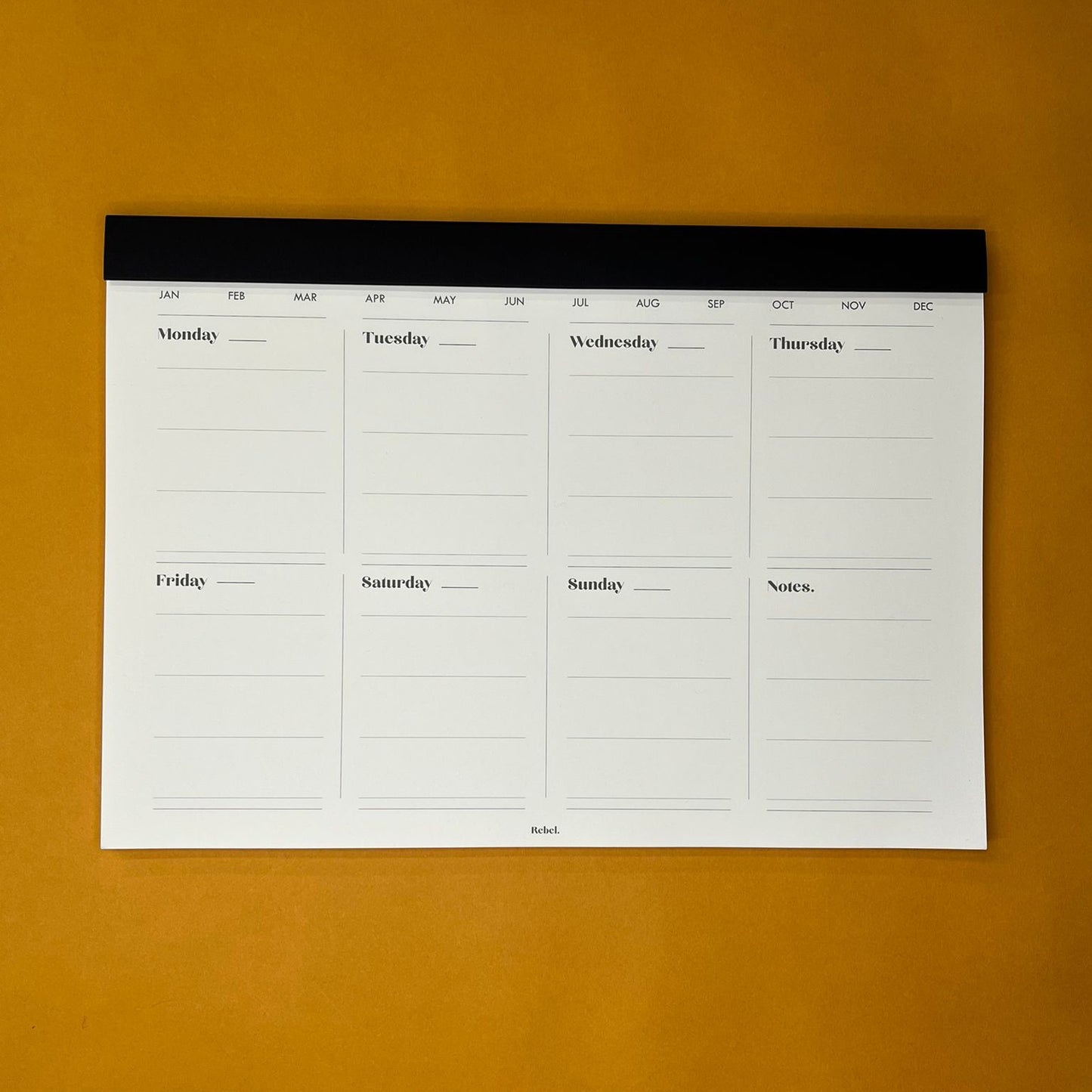 Black desk planner with weekly text on yellow background