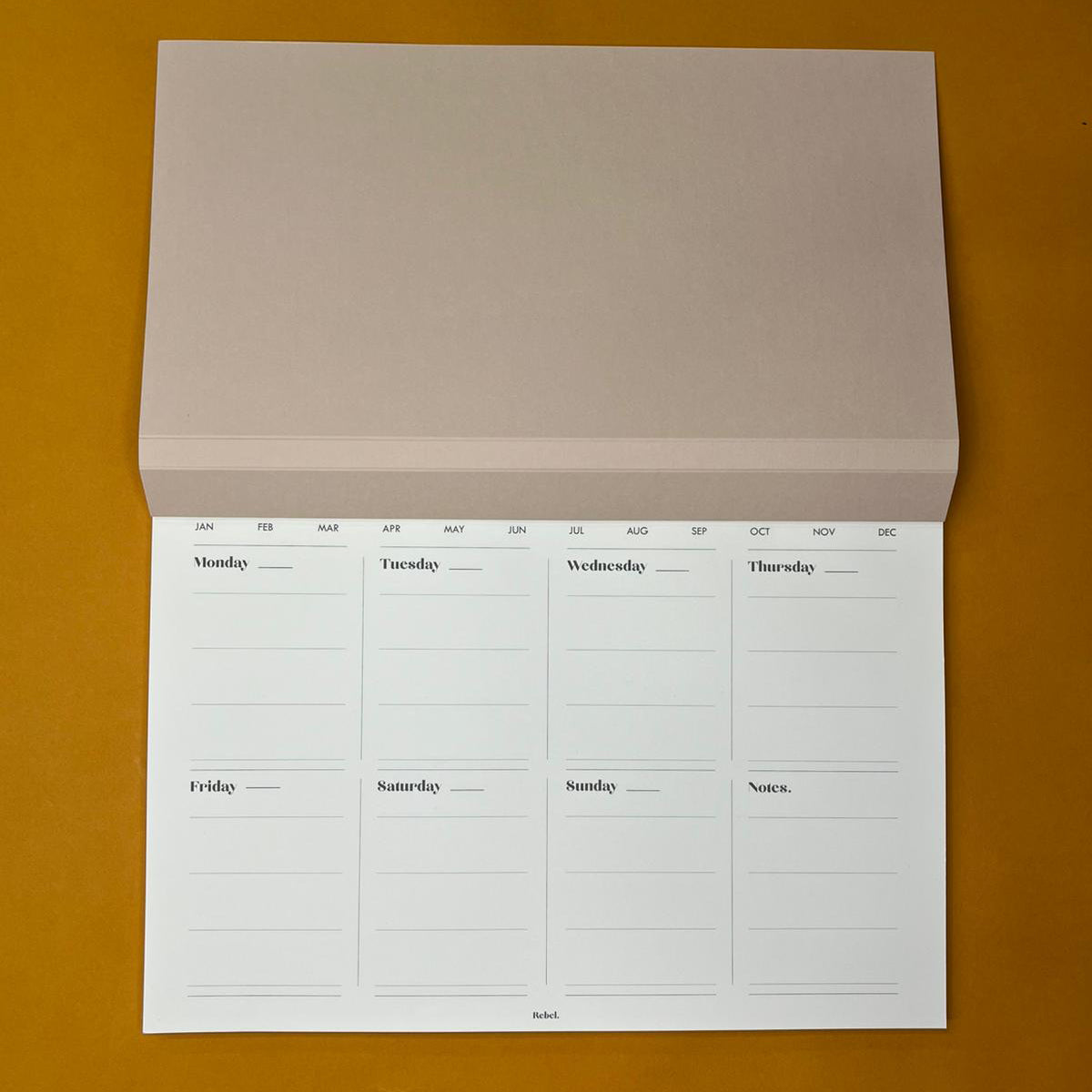 Beige desk planner with weekly layout on yellow background